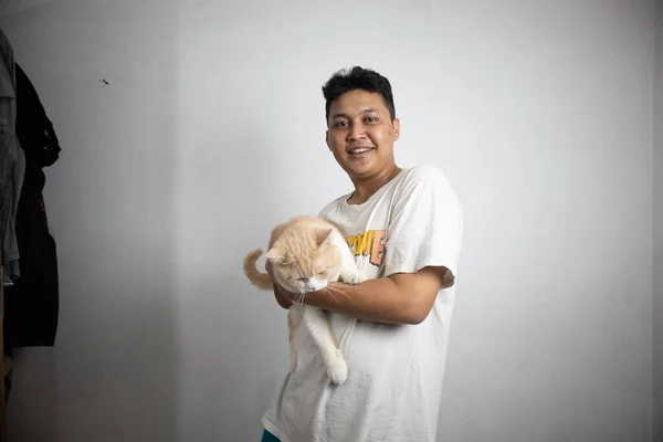Ritratto Felice Uomo Indonesiano Che Tiene Gatto Con Braccia Casa Foto Stock Royalty Free