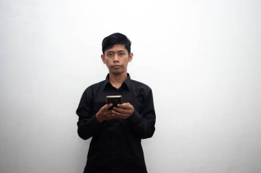 Siyahlı Asyalı adam beyaz arka planda akıllı telefon tutuyor.