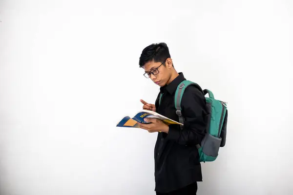 Asian man in black with glasses, backpack and book in hand is studying