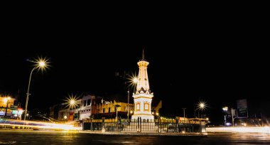 Yogyakarta, Endonezya - 14 Ocak 2024: Motosiklet ve arabaların hafif efektleriyle geceleyin Tugu Jogja. Tugu Yogyakarta 'da yavaş çekim tekniği.