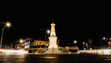 Yogyakarta, Endonezya - 14 Ocak 2024: Motosiklet ve arabaların hafif efektleriyle geceleyin Tugu Jogja. Tugu Yogyakarta 'da yavaş çekim tekniği.