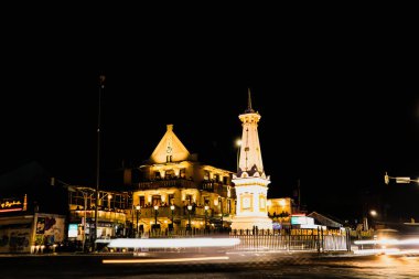 Yogyakarta, Endonezya - 14 Ocak 2024: Motosiklet ve arabaların hafif efektleriyle geceleyin Tugu Jogja. Tugu Yogyakarta 'da yavaş çekim tekniği.