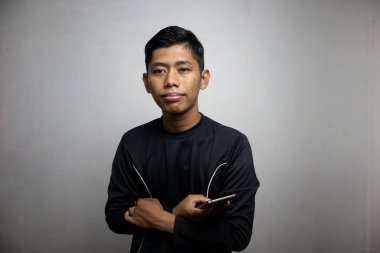 Siyah elbiseli yakışıklı Asyalı adam akıllı telefon kullanıyor, beyaz stüdyo geçmişi var. 