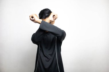 Siyah elbiseli duygusal Asyalı adam beyaz stüdyo arka planında poz veriyor. 