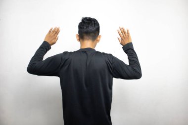 Siyah elbiseli Asyalı bir adamın beyaz stüdyo arka planında duruşu. 