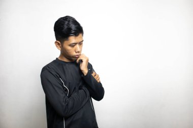 Siyah elbiseli duygusal Asyalı adam beyaz stüdyo arka planında poz veriyor. 