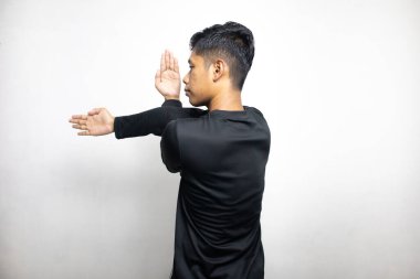 Siyah elbiseli Asyalı bir adamın beyaz stüdyo arka planında duruşu. 