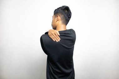 Siyah elbiseli Asyalı bir adamın beyaz stüdyo arka planında duruşu. 