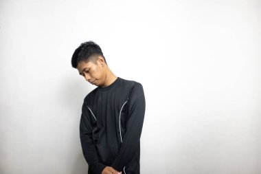 Siyah elbiseli duygusal Asyalı adam beyaz stüdyo arka planında poz veriyor. 