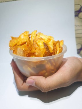 Beyaz arka planda izole edilmiş patates cipsi dolu bir kaseyle erkek eli. 