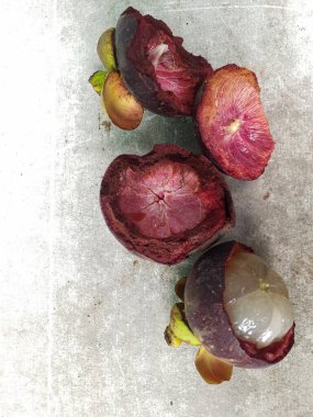 Mangosteen ve enine kesitler, mangosteen meyvelerinin kraliçesinin kalın mor derisini ve beyaz etini gösteriyor. Lezzetli mangosteen meyvesi yakın plan.