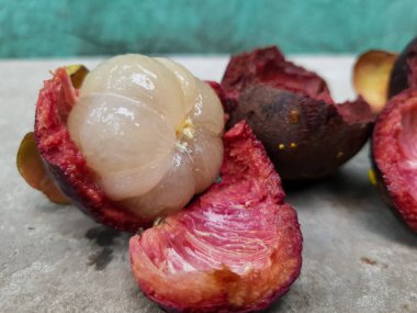 Mangosteen ve enine kesitler, mangosteen meyvelerinin kraliçesinin kalın mor derisini ve beyaz etini gösteriyor. Lezzetli mangosteen meyvesi yakın plan.