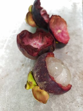 Mangosteen ve enine kesitler, mangosteen meyvelerinin kraliçesinin kalın mor derisini ve beyaz etini gösteriyor. Lezzetli mangosteen meyvesi yakın plan.