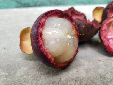 Mangosteen ve enine kesitler, mangosteen meyvelerinin kraliçesinin kalın mor derisini ve beyaz etini gösteriyor. Lezzetli mangosteen meyvesi yakın plan.