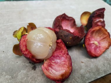 Mangosteen ve enine kesitler, mangosteen meyvelerinin kraliçesinin kalın mor derisini ve beyaz etini gösteriyor. Lezzetli mangosteen meyvesi yakın plan.