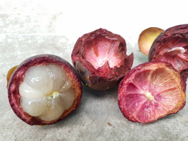 Mangosteen ve enine kesitler, mangosteen meyvelerinin kraliçesinin kalın mor derisini ve beyaz etini gösteriyor. Lezzetli mangosteen meyvesi yakın plan.