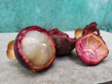 Mangosteen ve enine kesitler, mangosteen meyvelerinin kraliçesinin kalın mor derisini ve beyaz etini gösteriyor. Lezzetli mangosteen meyvesi yakın plan.