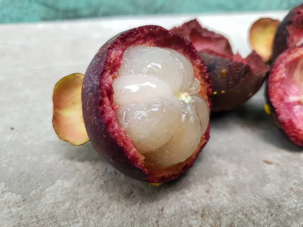 Mangosteen ve enine kesitler, mangosteen meyvelerinin kraliçesinin kalın mor derisini ve beyaz etini gösteriyor. Lezzetli mangosteen meyvesi yakın plan.