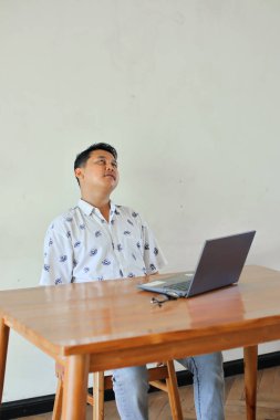 Laptop bilgisayarı olan genç bir adam masada oturuyor. 