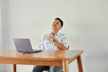 Laptop bilgisayarı olan genç adam masada oturuyor. 