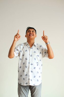 Genç mutlu Asyalı adam gülümseyerek fotokopi alanını işaret ediyor.
