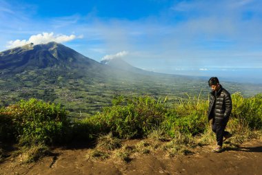 Genç adam nefes kesen manzaranın tadını çıkarıyor Dağlar ve güzel bulutlar sabahları                                  