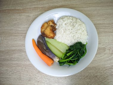 Pilav, sebze ve balık yan yemekleriyle dolu sağlıklı yemek menüsünün en üst görüntüsü.