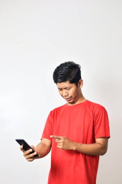 Kırmızı tişörtlü adam akıllı telefonunu kullanıyor.