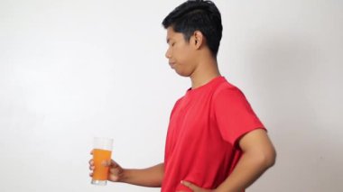 Genç mutlu adam beyaz arka planda portakal suyu içiyor..