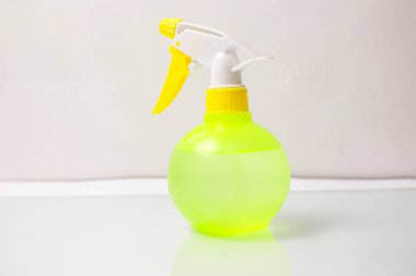 Beyaz zemin üzerinde sarı sıvı bulunan el dezenfektanı ve şişe.