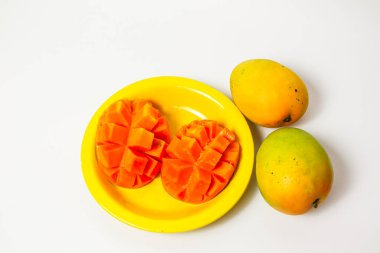 Beyaz arka planda izole edilmiş sarı tabakta tam ve dilimlenmiş mango, taze turuncu mango. 