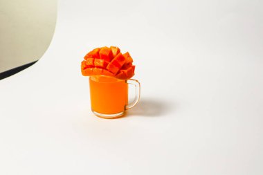 Beyaz arka planda dilimlenmiş mangolu bir bardak mango suyu 