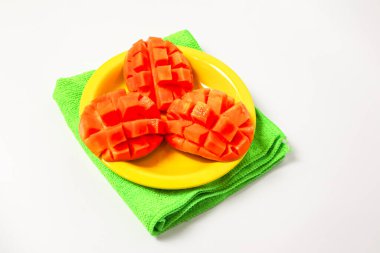 Beyaz arka planda izole edilmiş sarı bir tabakta mango dilimleri.