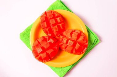 Beyaz arka planda izole edilmiş sarı bir tabakta mango dilimleri.