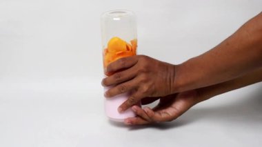 Mango suyu yapımında kullanılan küçük taşınabilir blender, beyaz arka planda taze mango suyu.