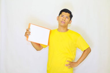 Asyalı genç adam sarı tişörtlü, pano düşünceli, stüdyo fotoğrafı. 