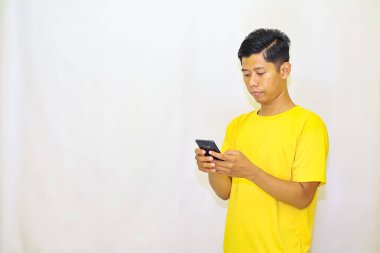 Beyaz arka planda cep telefonu olan yakışıklı Asyalı genç adam.