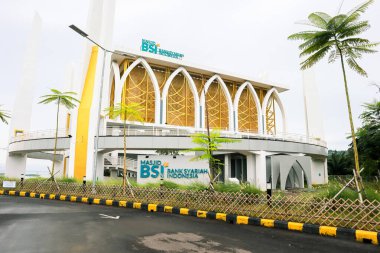 Bakauheni, January 17, 2025, exterior view of Masjid BSI Bank Syariah Indonesia with palm trees and a fence. clipart