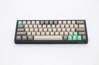 Lampung, 23 Ocak 2025, yeşil ve gri tuşlu siyah mekanik bir klavye beyaz bir yüzey üzerindedir.