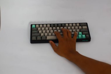 Lampung, January 23 2025, A hand is typing on a black keyboard with gray and teal keycaps. clipart