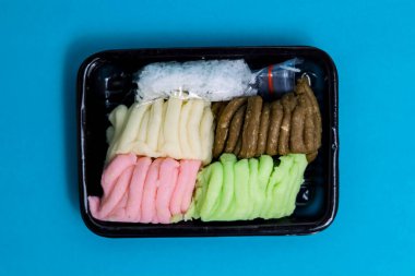 Geleneksel Endonezya atıştırmalığı Getuk Trio 'nun canlı bir dizisi, siyah bir tepside sergilenmektedir..