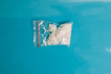 Parlak mavi arka planda bir çanta dolusu tatlı hindistan cevizi gevreği..