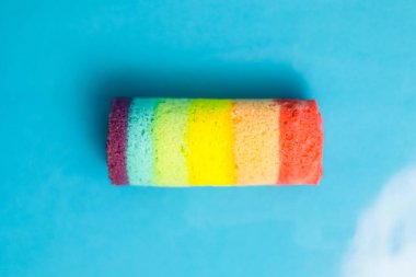 Mavi arka planda nefis bir gökkuşağı pastası rulosu, üst manzara yakın..