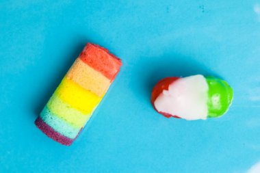 Renkli bir pasta ve jöleli şekerin yakın plan görüntüsü açık mavi bir fonda..