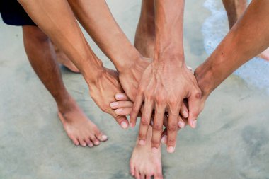 Birkaç el kumlu bir plajda birleşerek birlik hissini ve takım amaçlarını yansıtıyor..