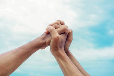 Parlak mavi gökyüzüne sıkıca kenetlenmiş iki el birliği simgeliyor..