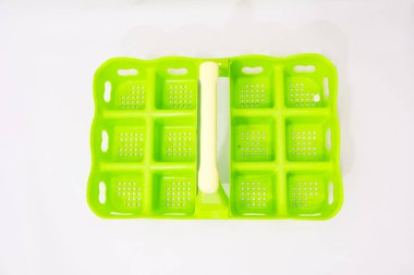 Temiz beyaz arka planda duran parlak yeşil buz küpü tepsisi ferahlatıcı içecekler hazırlamaya hazır.