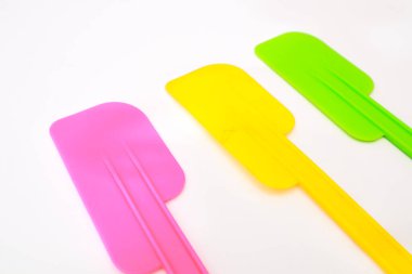 Üç canlı silikon spatula yemek pişirmek için ideal beyaz arka planda duruyor.
