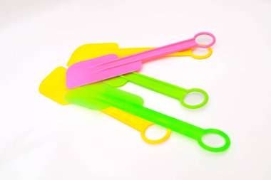 Beyaz yüzeyde parlak stüdyo ışıklarıyla çekilen renkli silikon spatula yığınları.