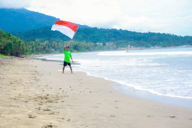 Genç bir adam Endonezya 'nın Bağımsızlık Günü' nü güzel bir tropik plajda neşeyle kutluyor..